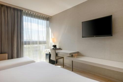 a hotel room with a bed and a television on the wall at AC Hotel San Cugat by Marriott in Sant Cugat del Vallès