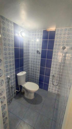 a bathroom with a toilet and a shower with blue tiles at Azza Home in Cochin
