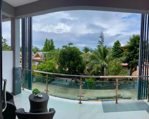 a balcony with a view of a pool and trees at Lanta Just Come Bungalow in Ko Lanta