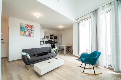 un salon avec un canapé et une chaise bleue dans l'établissement Triplex terrasse proche métro - Ty ar Mabilay, à Rennes