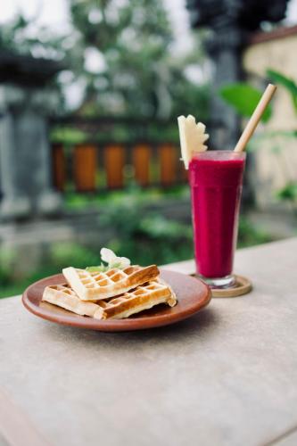 a plate of waffles and a drink on a table at Abian Bali Resort Amed in Amed