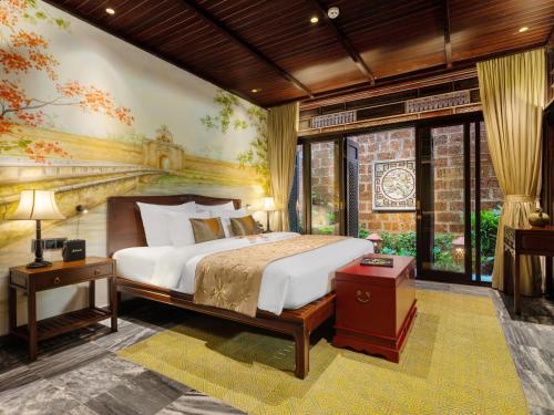 a bedroom with a bed and a painting on the wall at Ancient Huế Garden Houses in Hue