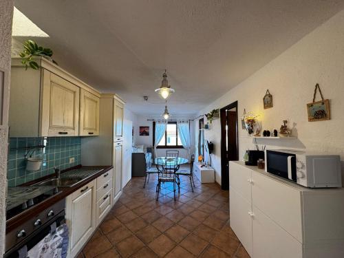 Una cocina con gabinetes blancos y una mesa con sillas. en Sardegna Porto San Paolo, en Porto San Paolo