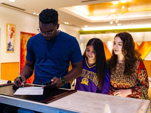 a man signing a piece of paper on a table with two girls at ibis Styles Kyoto Shijo in Kyoto
