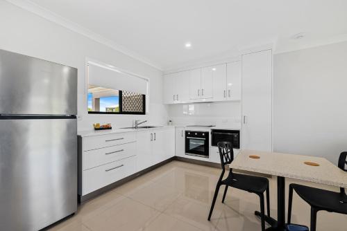 a kitchen with white cabinets and a stainless steel refrigerator at Casa Nostra Motel in Rockhampton