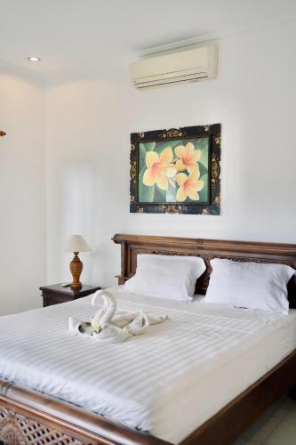 a bed with white sheets and a picture on the wall at Abian Bali Resort Amed in Amed