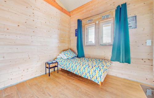 a room with a bed and a window with blue curtains at Awesome Home In Milly-Sur-Thérain in Milly-sur-Thérain