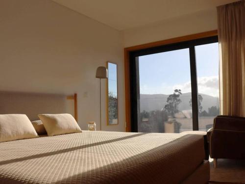 ein Schlafzimmer mit einem großen Bett mit einem großen Fenster in der Unterkunft Casa do Norte in Póvoa de Lanhoso