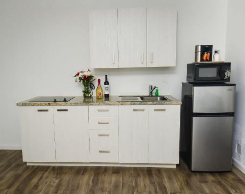 a kitchen with white cabinets and a sink and a refrigerator at Regency Inn & Suites Sarasota in Sarasota
