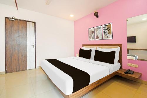 a bedroom with a large bed with a pink wall at Townhouse Mancheswar Bhubaneswar Formerly Kamla Inn in Bhubaneshwar