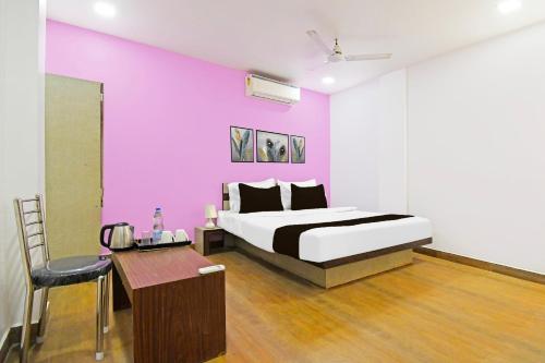 a bedroom with a bed and a purple wall at Townhouse Mancheswar Bhubaneswar Formerly Kamla Inn in Bhubaneshwar