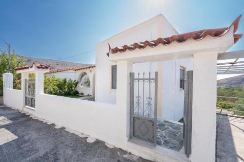 a white house with a gate with a view at Maria's Home Aegina in Kondós