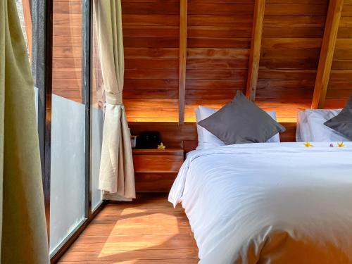 a bedroom with a white bed and a window at Hidden Den Villa Ubud in Ubud
