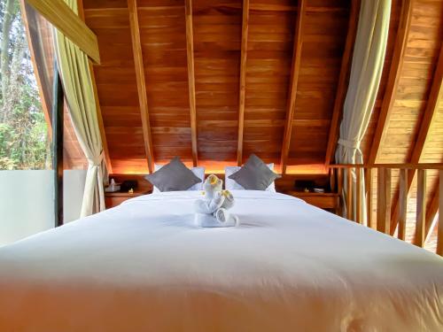 a bedroom with a white bed with a wooden ceiling at Hidden Den Villa Ubud in Ubud