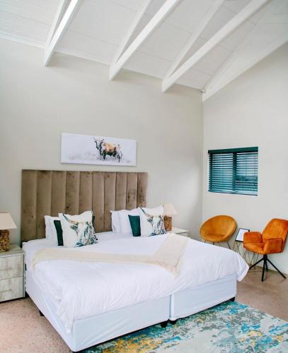 a bedroom with a large white bed with a wooden headboard at Elements Sunrise Bush Lodge in Bela-Bela