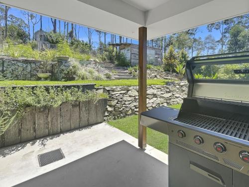 an outdoor kitchen with a grill in a backyard at The Nest by Batemans Bay in Batemans Bay
