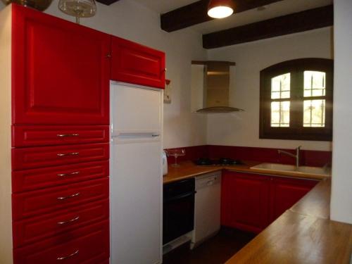 une cuisine avec des armoires rouges et un réfrigérateur blanc dans l'établissement Maison 2 chambres tout confort au calme, à Solliès-Toucas