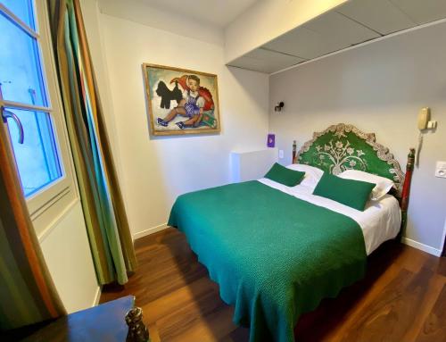 a bedroom with a green and white bed and a window at Hôtel des Templiers in Collioure