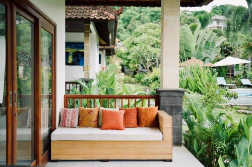 a porch with a bench with colorful pillows on it at Abian Bali Resort Amed in Amed