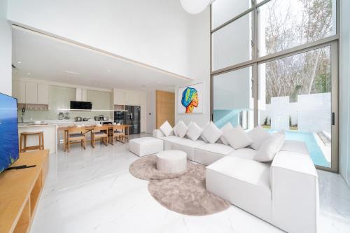 a living room with a white couch and a kitchen at Brand New & Modern Luxury 4BR Pool Villa in Residence Lux Pride 2 V12 in Bang Tao Beach
