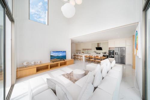 a living room with a white couch and a kitchen at Brand New & Modern Luxury 4BR Pool Villa in Residence Lux Pride 2 V12 in Bang Tao Beach