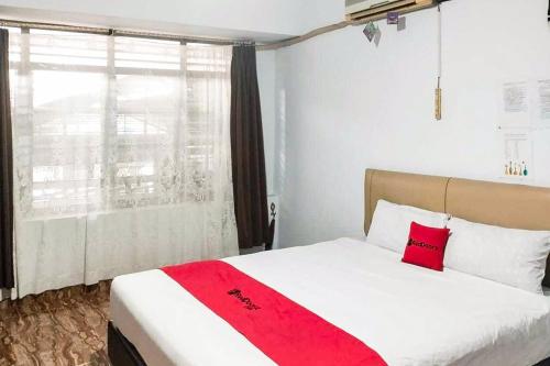 a bedroom with a bed with a red blanket on it at RedDoorz at Amanah Syariah Residence Tanjung Karang Lampung in Tanjungkarang