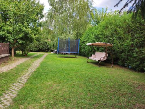 a park with a bench and an umbrella in the grass at Helga Apartman Siófok in Siófok
