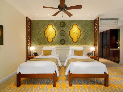 a bedroom with three beds and a ceiling fan at Ancient Huế Garden Houses in Hue
