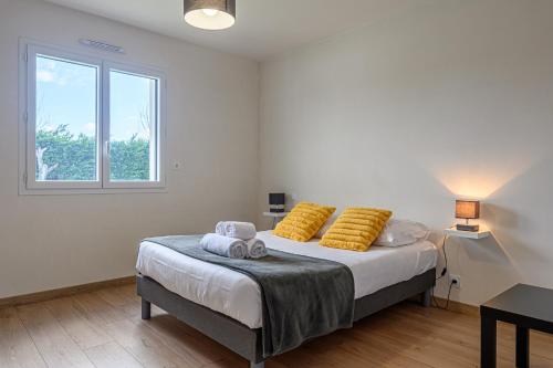 a bedroom with a bed with yellow pillows and a window at Domaine de Larmor - Maison proche plages in Damgan
