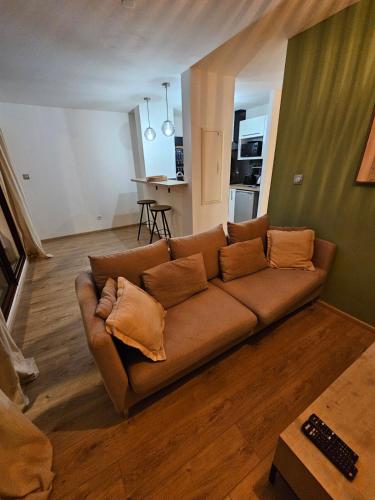 a living room with a brown couch and a kitchen at La Riviera in Saint-Denis