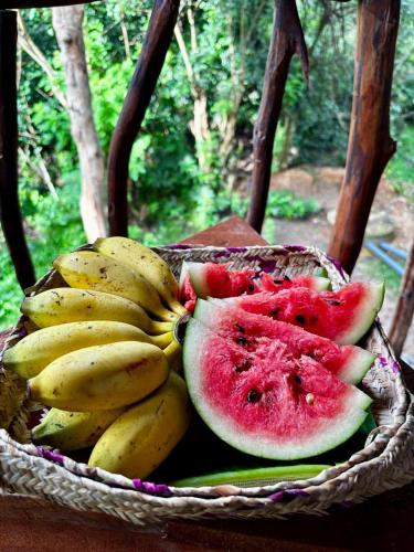 a basket of bananas and watermelons on a table at Atha Tree House in Habarana