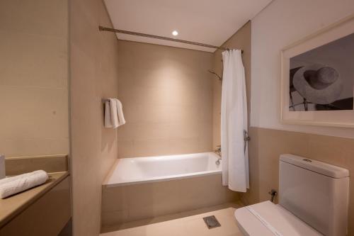 a bathroom with a bath tub and a toilet at Otolo Homes with Free Yas Theme Park Tickets in Abu Dhabi