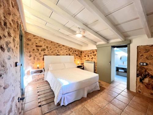 ein Schlafzimmer mit einem weißen Bett und einer Steinwand in der Unterkunft Cream homes Son Celles, ETV3533 in Sencelles