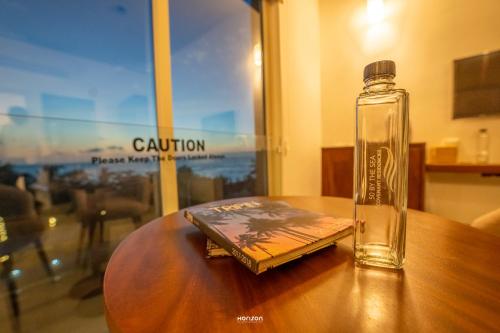 a glass bottle sitting on top of a table with a book at 50 By The Sea in Dehiwala
