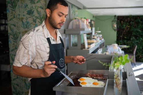 a man in an apron preparing eggs on a grill at Villa Sassolini Suite & Rooms - Country Boutique Hotel in Montevarchi
