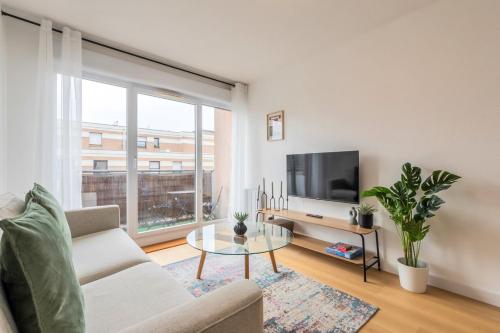 Una sala de estar con un sofá y un televisor. en Appartement une chambre avec parking et balcons, en Tourcoing