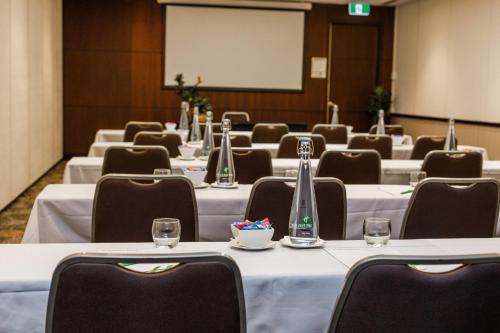 a conference room with tables and chairs and a whiteboard at Holiday Inn Perth City Centre by IHG in Perth