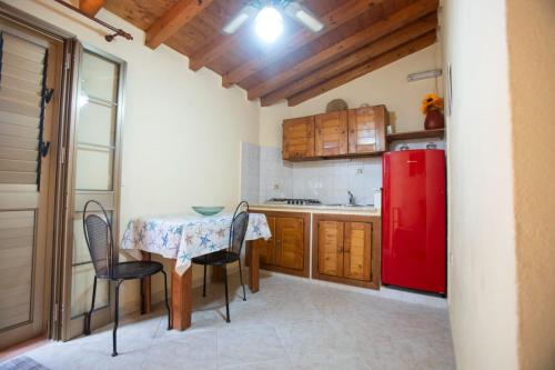 een keuken met een tafel en een rode koelkast bij Le Villette Luisa in Lampedusa