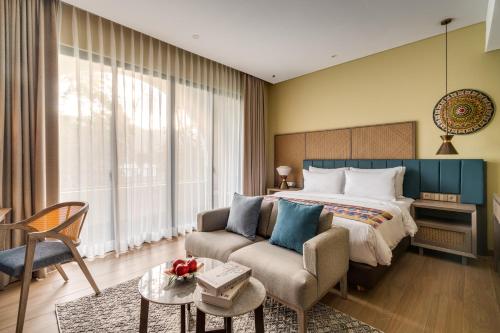 a bedroom with a bed and a couch and a chair at Sima Hotel Kuta Lombok in Kuta Lombok