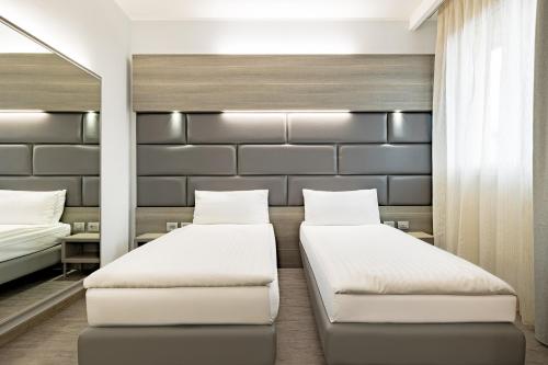 a bedroom with two beds and a mirror at Just Hotel Saronno in Saronno