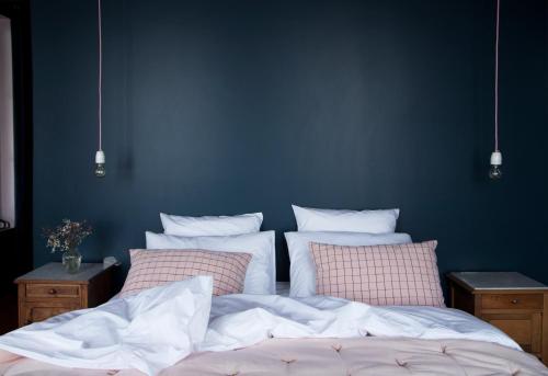 a bed with white sheets and pink pillows in a bedroom at La Maison Plûme in Villequier