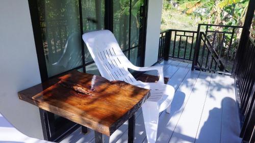 a white chair and a wooden table on a balcony at TinyHouse at TigerCave in Ko Bu Bu
