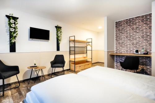 a bedroom with a bed and chairs and a fireplace at Hotel Apfelblüte in Wendorf