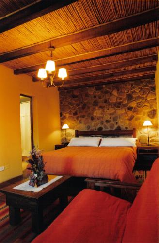 a bedroom with two beds and a stone wall at Rincón De Fuego in Tilcara