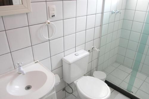 a white bathroom with a toilet and a sink at Pousada Leão do Mar in Abraão