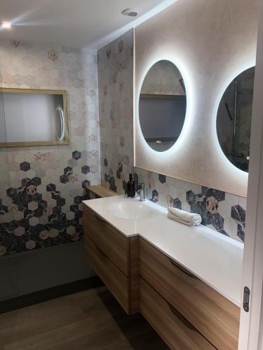 La salle de bains est pourvue d'un lavabo et de deux miroirs circulaires. dans l'établissement Les Platanes, à Duingt