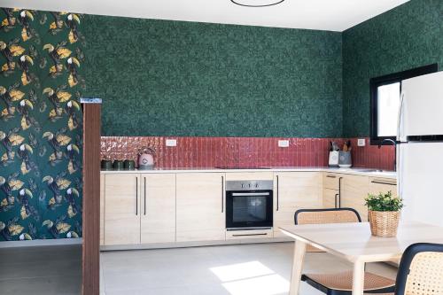 a kitchen with green walls and a table with chairs at ווילו בערבה in ‘En Yahav