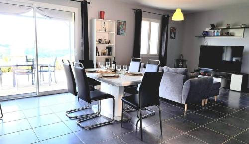 une salle à manger avec une table, des chaises et une télévision dans l'établissement Jolie maison à la campagne - magnifique vue - 6pers, à Carvès