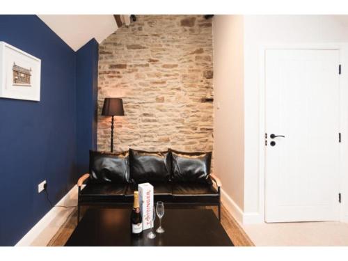 a black leather couch in a room with a brick wall at Deacons Bank Penthouses, Two Luxury Apartments in Chapel en le Frith