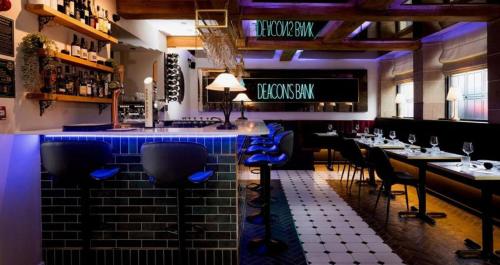 a restaurant with a bar with blue chairs and tables at Deacons Bank Penthouses, Two Luxury Apartments in Chapel en le Frith